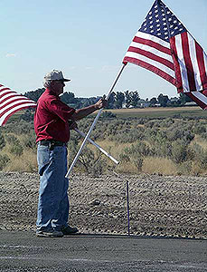 Older man waving two American flags at Crossroads Point's Patriot Day Healing Field