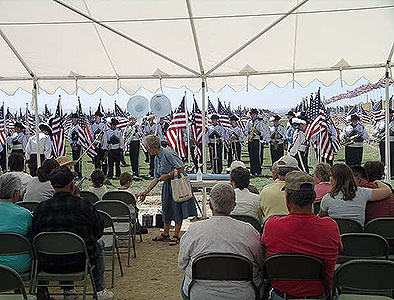 Elderly women greeting child with marching band in background at Crossroads Point's Patriot Day Healing Field
