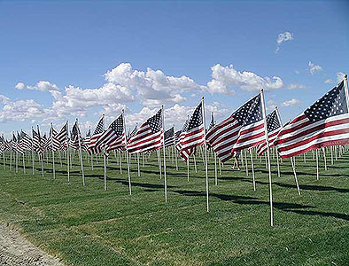 Rows of American flags against cloudy blue sky at Crossroads Point's Patriot Day Healing Field